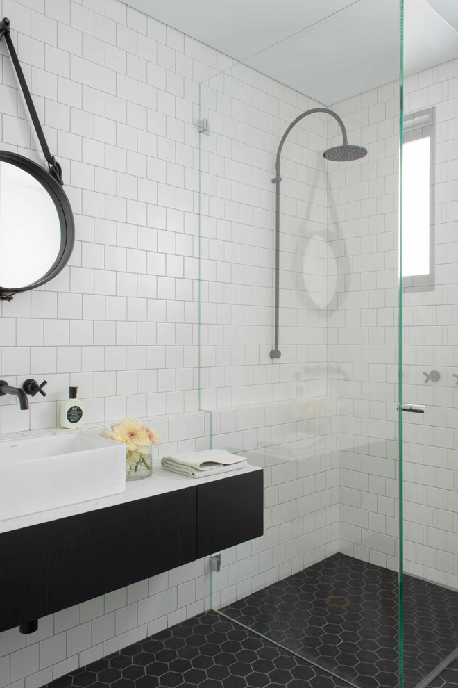 Photo of a contemporary bathroom in Sydney with a vessel sink, flat-panel cabinets, black cabinets, a curbless shower and white tile.