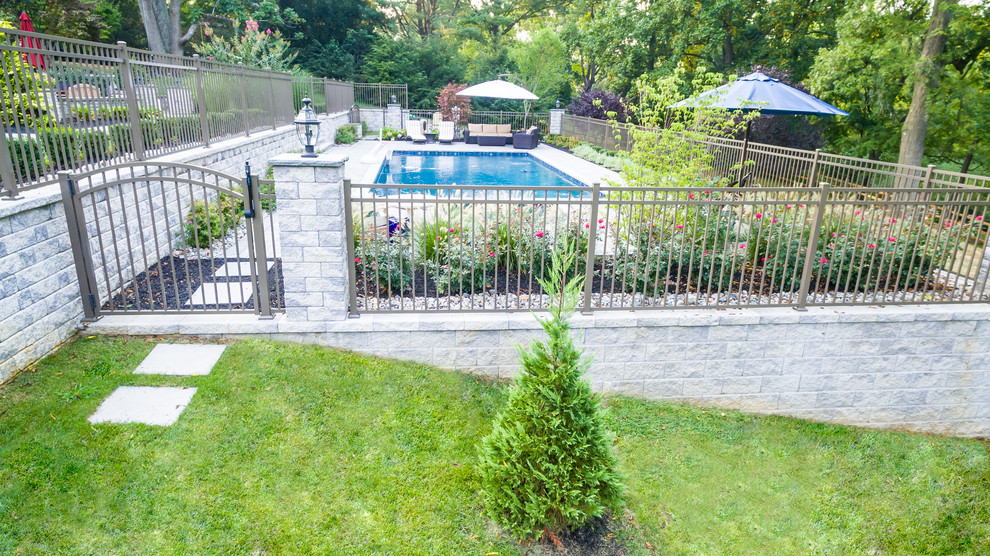 This is an example of a large modern backyard rectangular natural pool in New York with a hot tub and brick pavers.