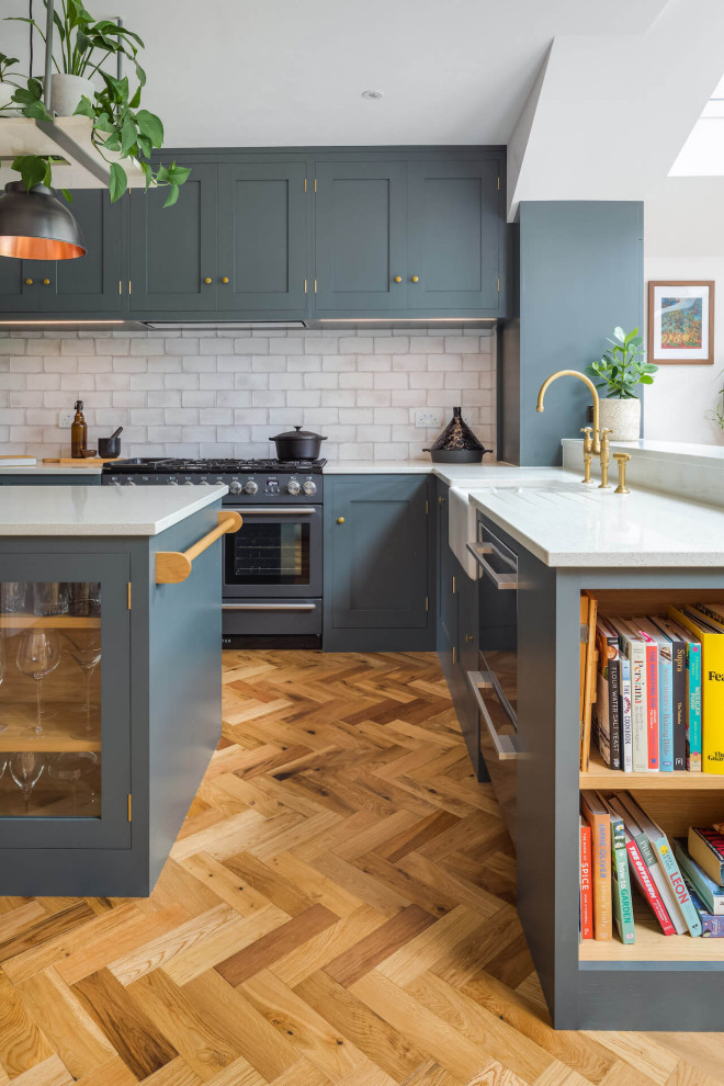Design ideas for a large transitional l-shaped open plan kitchen in London with shaker cabinets, grey cabinets, with island and white benchtop.