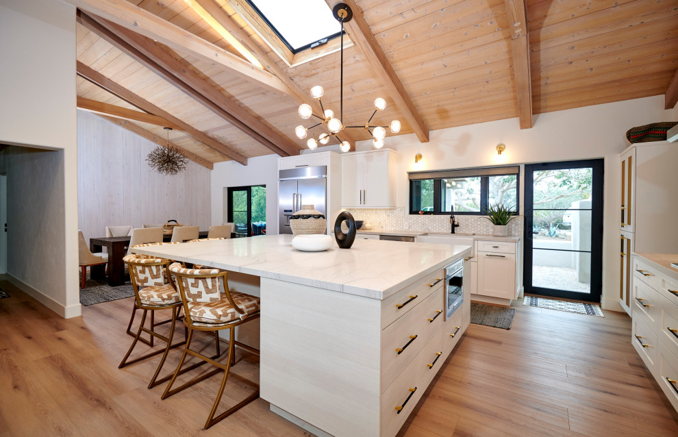 Exempel på ett stort klassiskt vit vitt kök, med en undermonterad diskho, luckor med infälld panel, vita skåp, bänkskiva i kvartsit, vitt stänkskydd, stänkskydd i marmor, rostfria vitvaror, mellanmörkt trägolv, en köksö och brunt golv