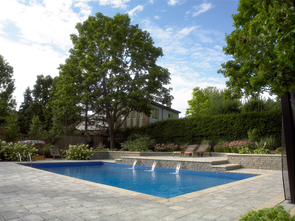 Design ideas for a large modern backyard rectangular natural pool in Toronto with a water feature and brick pavers.