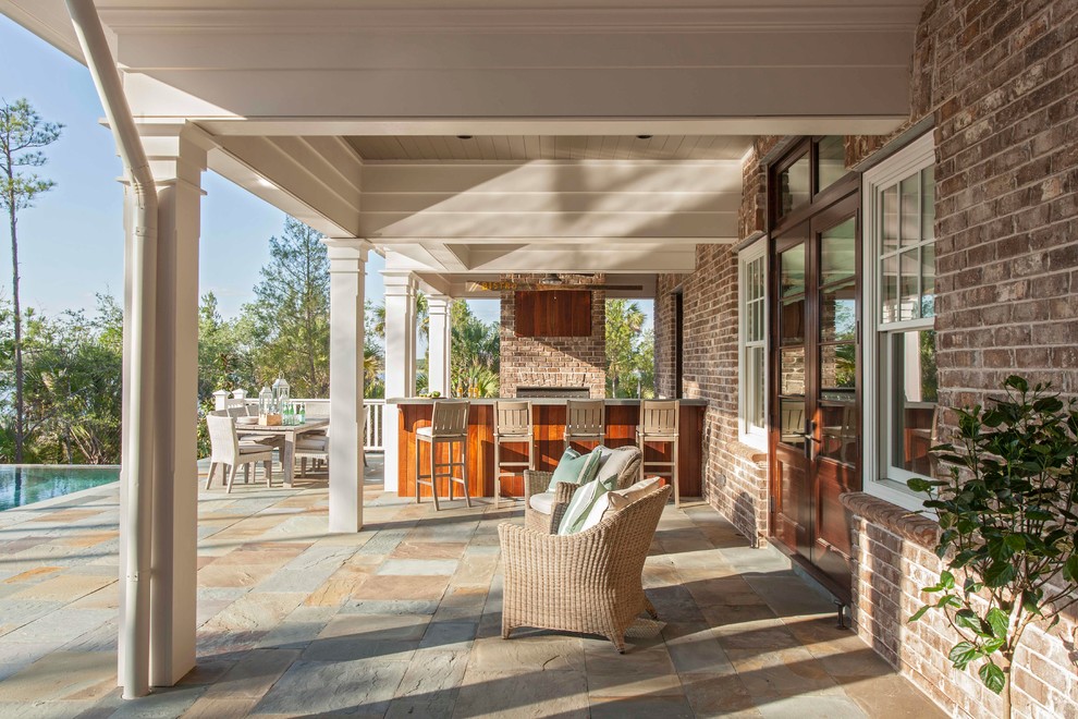 This is an example of an expansive transitional backyard deck in Charleston with an outdoor kitchen and a roof extension.