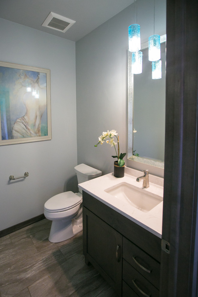 Small country 3/4 bathroom in Other with recessed-panel cabinets, dark wood cabinets, a two-piece toilet, blue walls, vinyl floors, an undermount sink and solid surface benchtops.