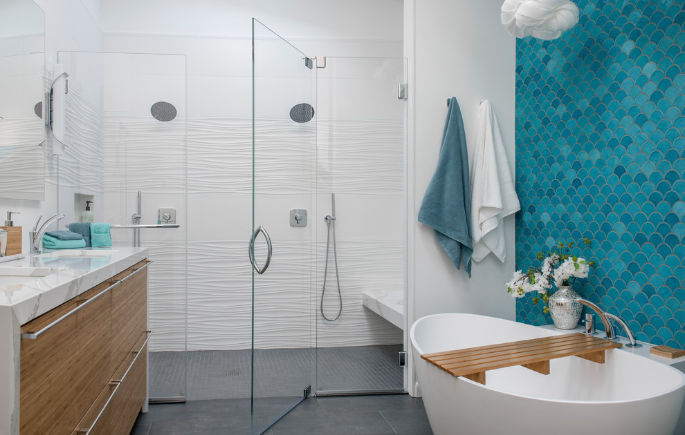 This is an example of a contemporary master bathroom in Boston with flat-panel cabinets, medium wood cabinets, a freestanding tub, a curbless shower, blue tile, white walls, an undermount sink, grey floor, a hinged shower door and a shower seat.