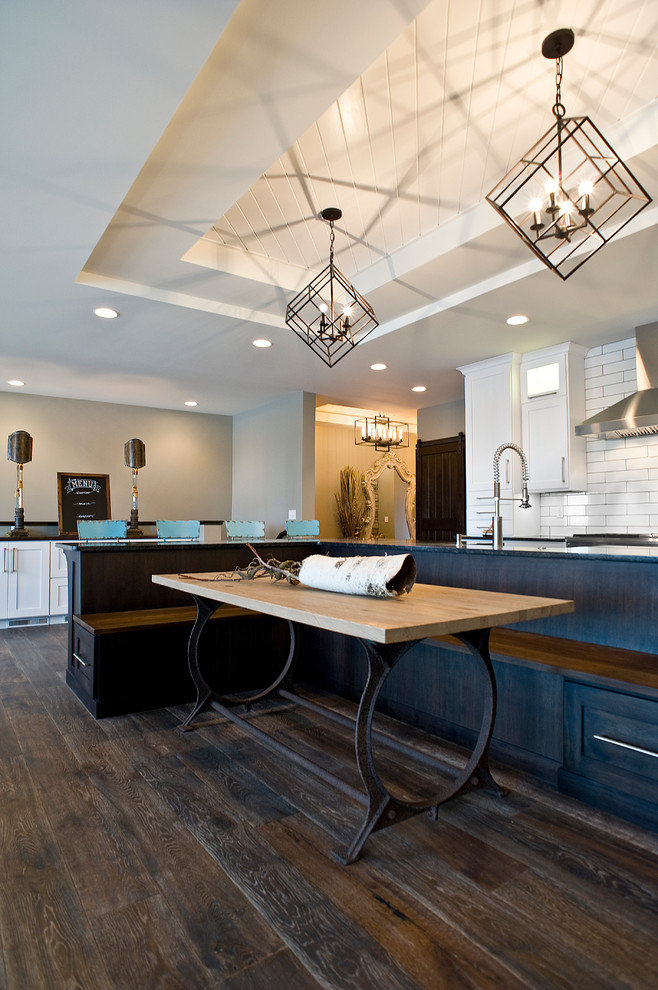 Inspiration for a large transitional l-shaped dark wood floor and brown floor eat-in kitchen remodel with an undermount sink, white cabinets, granite countertops, white backsplash, subway tile backsplash, stainless steel appliances, an island and shaker cabinets
