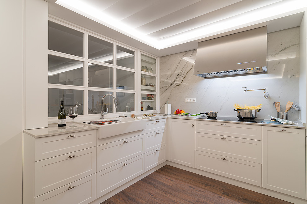 Inspiration for a transitional l-shaped open plan kitchen in Bilbao with a double-bowl sink, raised-panel cabinets, white cabinets, granite benchtops, limestone splashback, black appliances, medium hardwood floors and brown floor.