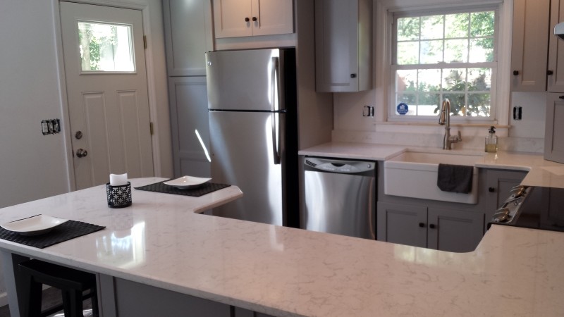 Small minimalist l-shaped kitchen photo in Philadelphia with a farmhouse sink, recessed-panel cabinets, white cabinets, stainless steel appliances and a peninsula