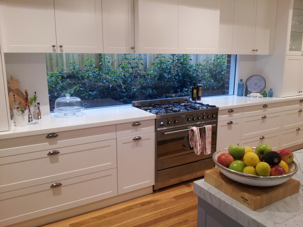 Inspiration for a large transitional eat-in kitchen in Sydney with a double-bowl sink, recessed-panel cabinets, white cabinets, marble benchtops, white splashback, stainless steel appliances, light hardwood floors and with island.