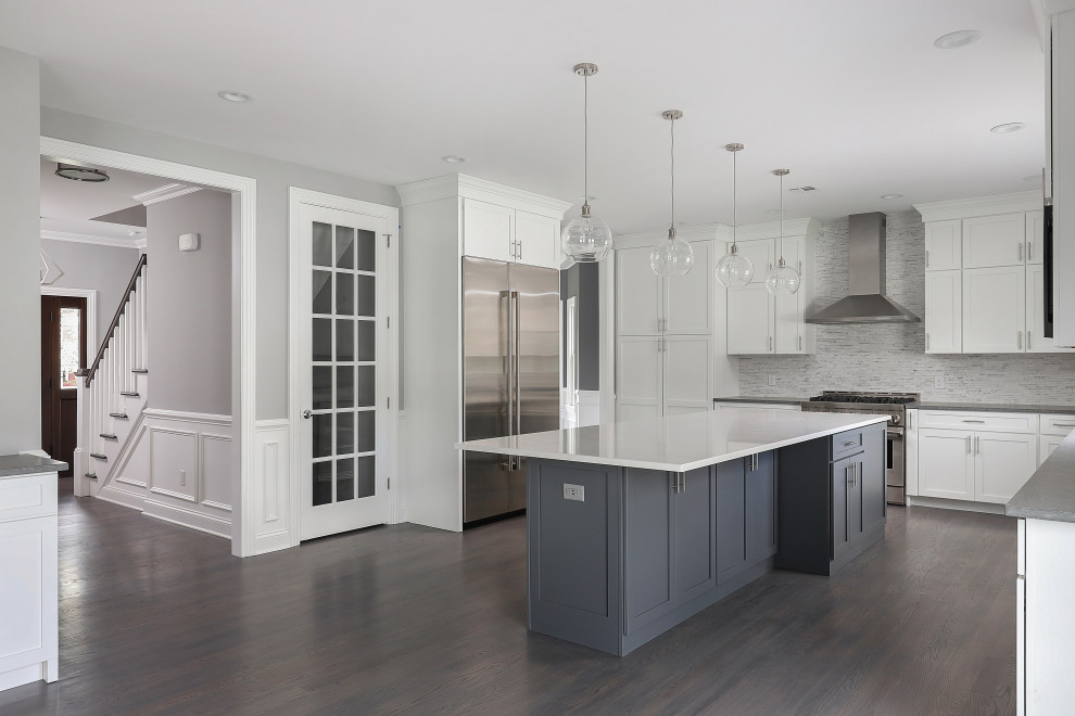 Design ideas for a large classic u-shaped open plan kitchen in Newark with a submerged sink, shaker cabinets, white cabinets, stainless steel appliances, an island and brown floors.