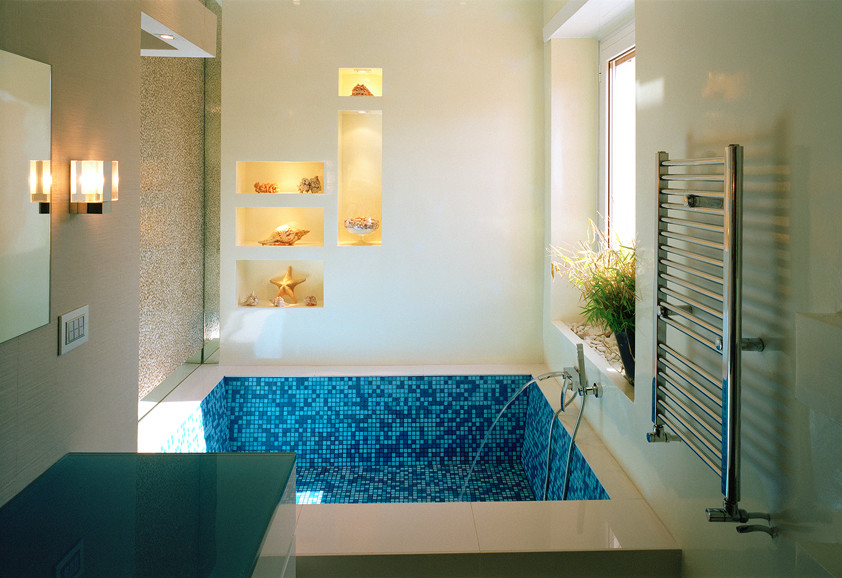 Photo of a mid-sized contemporary bathroom in Rome with pebble tile, white walls, vinyl floors, turquoise floor, flat-panel cabinets, turquoise cabinets, an alcove tub, a two-piece toilet, an integrated sink and glass benchtops.
