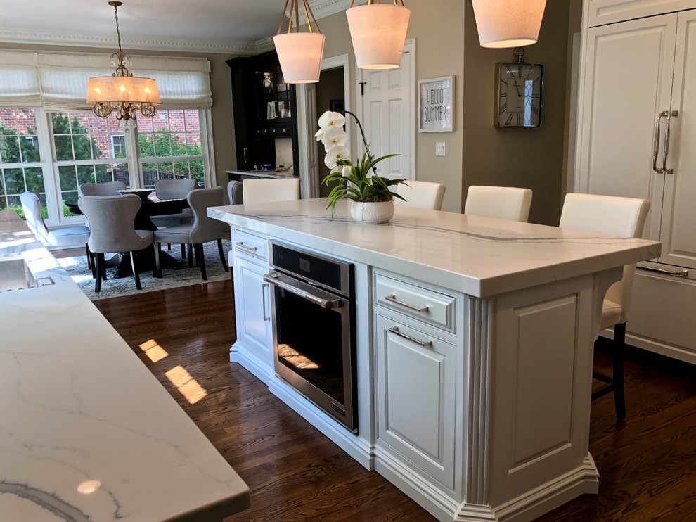 Eat-in kitchen - large transitional u-shaped dark wood floor and brown floor eat-in kitchen idea in Chicago with an undermount sink, raised-panel cabinets, white cabinets, quartz countertops, gray backsplash, ceramic backsplash, stainless steel appliances, an island and white countertops