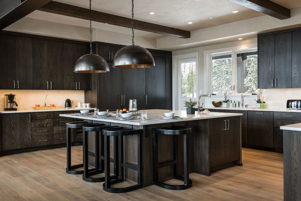 Country u-shaped kitchen in Salt Lake City with an undermount sink, flat-panel cabinets, dark wood cabinets, white splashback, panelled appliances, medium hardwood floors, with island and brown floor.
