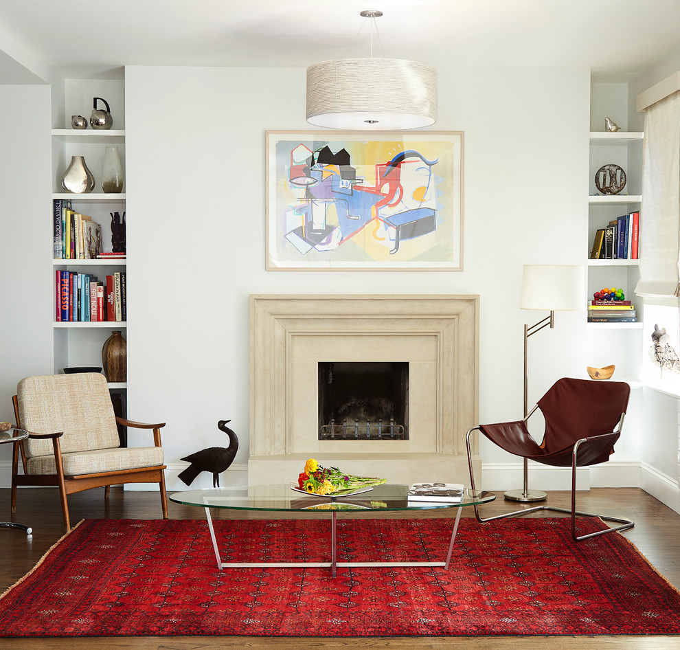Photo of a mid-sized transitional living room in New York with white walls, medium hardwood floors, a standard fireplace, no tv and a concrete fireplace surround.