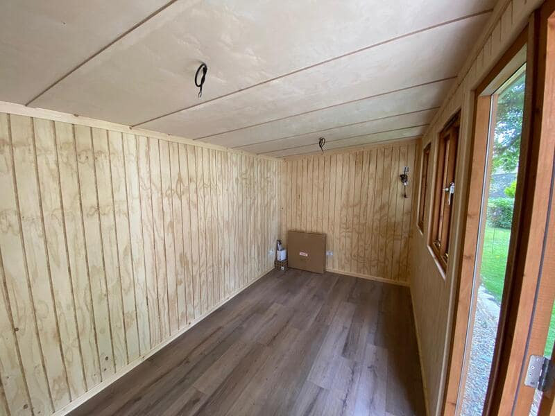Mid-sized contemporary home studio in Dorset with beige walls, laminate floors, a freestanding desk, brown floor and panelled walls.