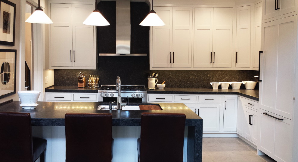 Inspiration for a mid-sized transitional l-shaped concrete floor and beige floor eat-in kitchen remodel with an undermount sink, shaker cabinets, white cabinets, granite countertops, black backsplash, stone slab backsplash, paneled appliances and a peninsula