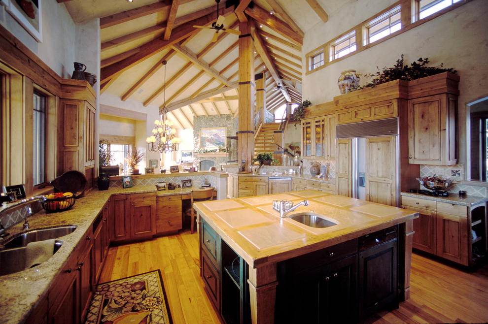 Eat-in kitchen - large rustic u-shaped medium tone wood floor and brown floor eat-in kitchen idea in Denver with an undermount sink, recessed-panel cabinets, medium tone wood cabinets, granite countertops, beige backsplash, glass tile backsplash, stainless steel appliances and an island