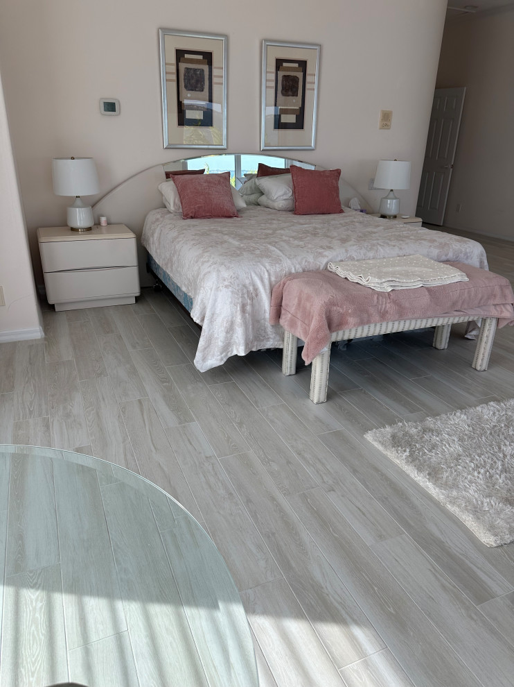 This is an example of a large beach style guest bedroom in Tampa with porcelain flooring, a standard fireplace, a stone fireplace surround, grey floors, a vaulted ceiling, wallpapered walls and pink walls.