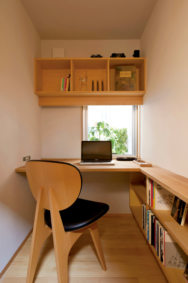 This is an example of a small scandinavian study room in Other with white walls, a built-in desk and light hardwood floors.