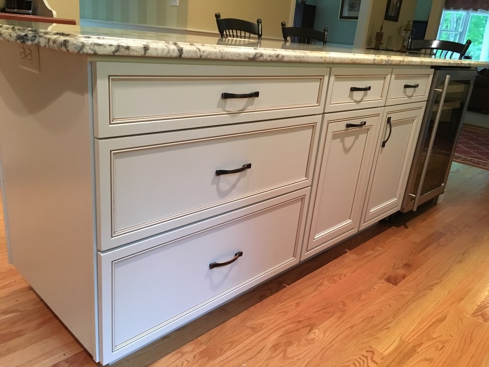Transitional u-shaped light wood floor eat-in kitchen photo in Boston with an undermount sink, raised-panel cabinets, granite countertops, subway tile backsplash, stainless steel appliances and an island