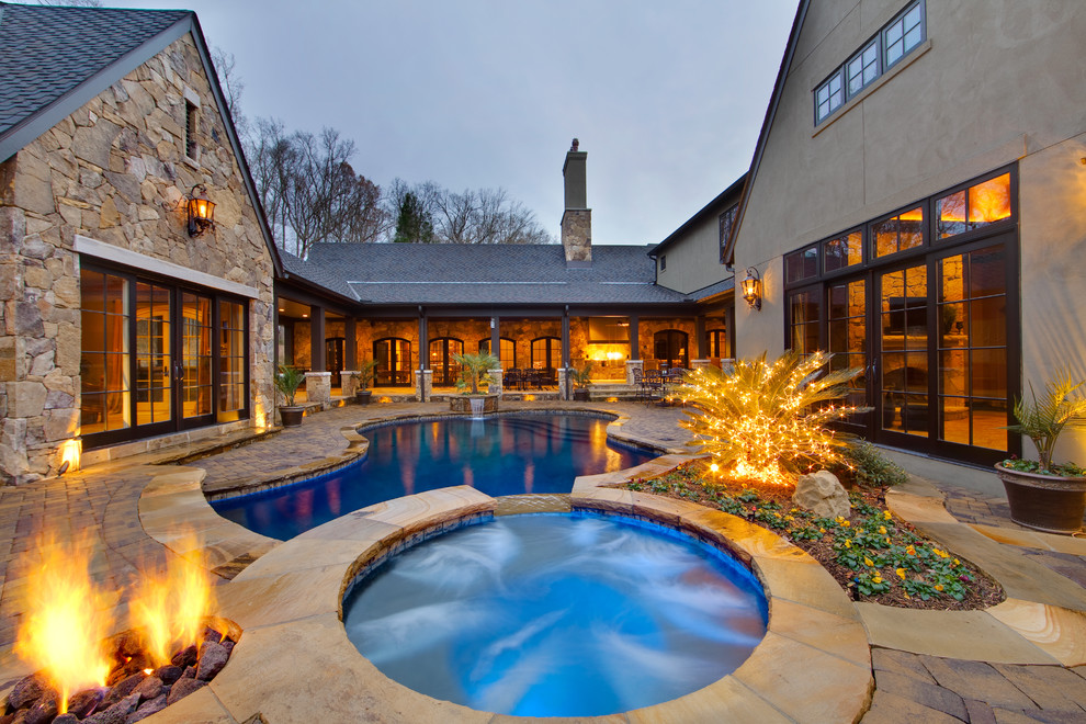 Design ideas for a traditional courtyard custom-shaped pool in Charlotte with natural stone pavers.