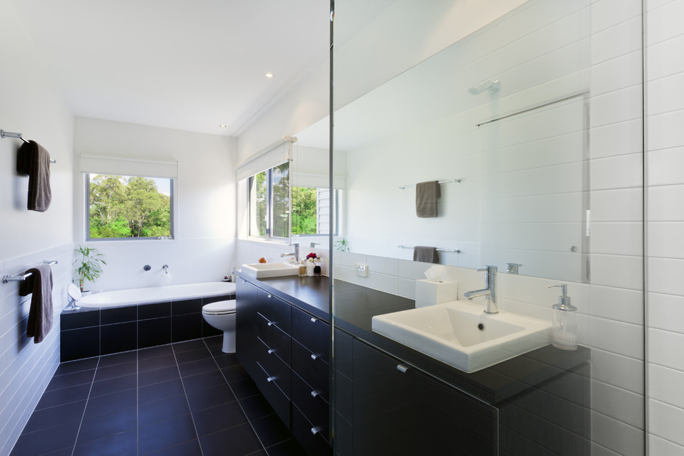 Photo of a large contemporary master bathroom in Los Angeles with a drop-in sink, flat-panel cabinets, black cabinets, wood benchtops, a corner tub, a corner shower, a one-piece toilet, ceramic tile, white walls, ceramic floors, black and white tile, black floor and a hinged shower door.