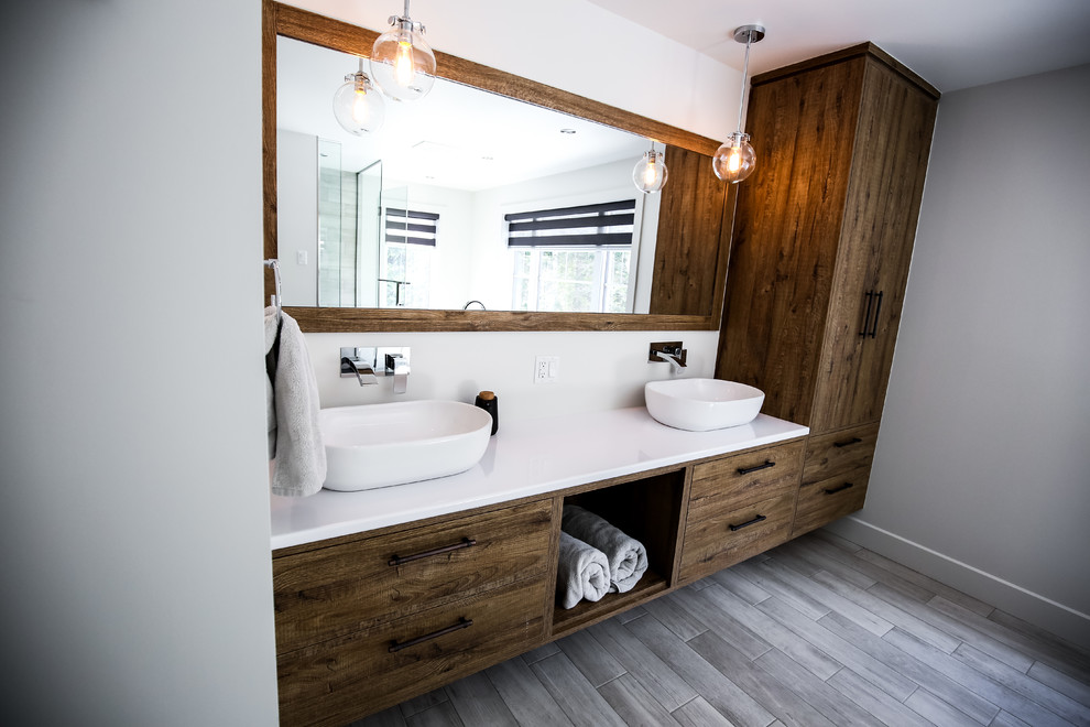 Design ideas for a large country master bathroom in Montreal with flat-panel cabinets, medium wood cabinets, a freestanding tub, a corner shower, black and white tile, porcelain tile, grey walls, porcelain floors, a vessel sink and laminate benchtops.