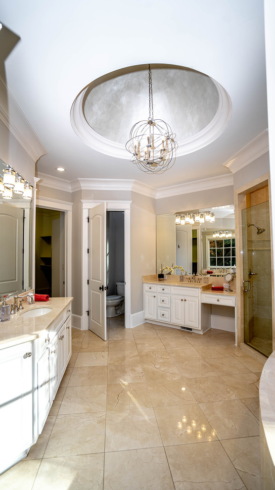 Example of a mid-sized transitional master beige tile and marble tile marble floor and beige floor freestanding bathtub design in Atlanta with raised-panel cabinets, white cabinets, a one-piece toilet, gray walls, an undermount sink, marble countertops, a hinged shower door and beige countertops