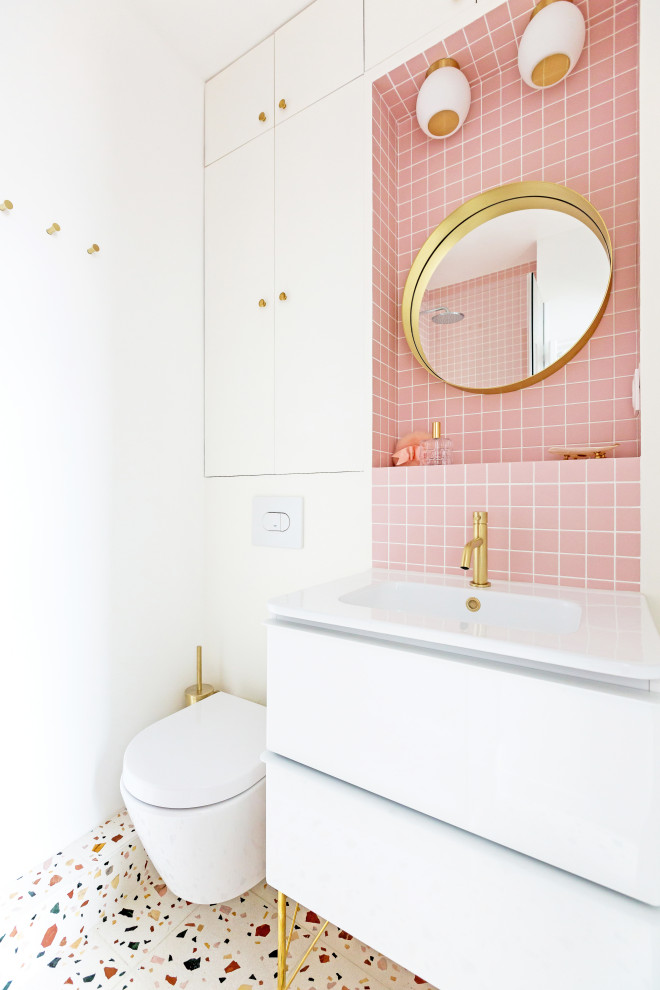 Small scandinavian master bathroom in Paris with beaded inset cabinets, white cabinets, a corner shower, a wall-mount toilet, pink tile, mosaic tile, white walls, terrazzo floors, a pedestal sink, tile benchtops, multi-coloured floor, a hinged shower door and pink benchtops.