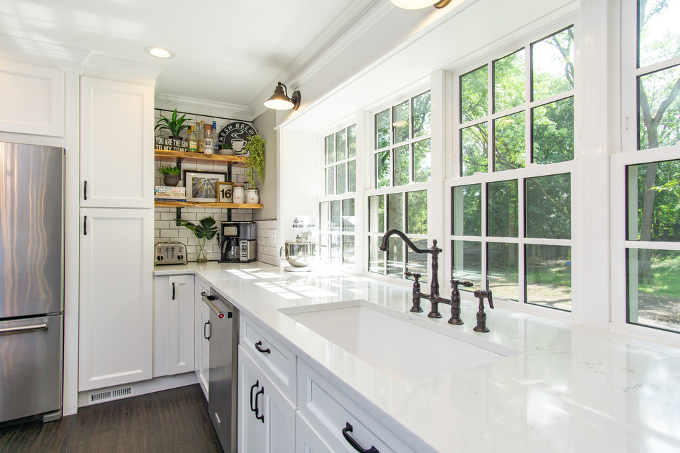 Large country eat-in kitchen in Philadelphia with shaker cabinets, white cabinets, quartz benchtops, white splashback, subway tile splashback, stainless steel appliances, with island and white benchtop.