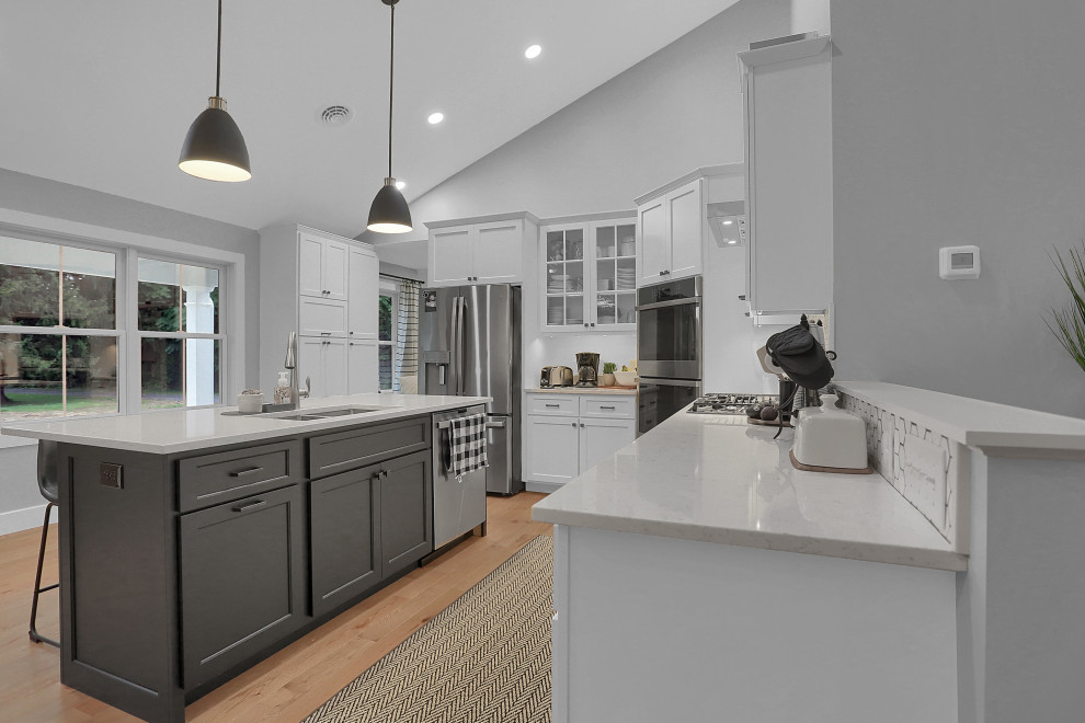 Example of a mid-sized transitional l-shaped open concept kitchen design with flat-panel cabinets, white cabinets, quartz countertops, gray backsplash, an island and white countertops