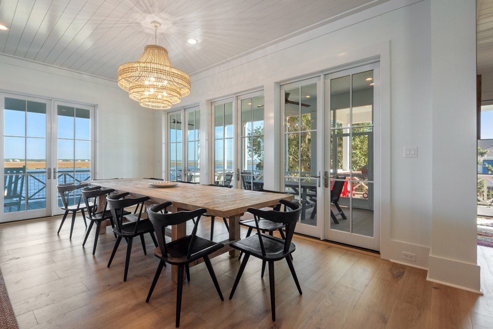 Beach style open plan dining in New Orleans with white walls, light hardwood floors, beige floor and timber.