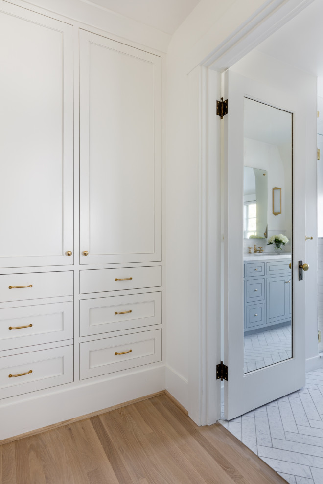 Inspiration for a mid-sized transitional gender-neutral light wood floor and brown floor built-in closet remodel in Seattle with white cabinets