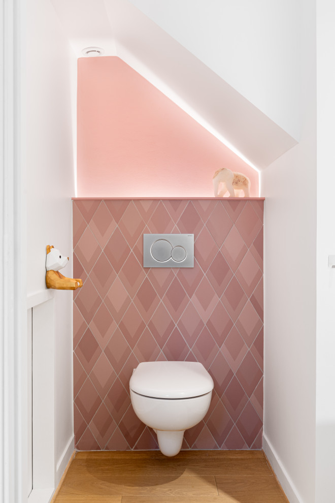 На фото: туалет в современном стиле с инсталляцией, розовой плиткой, розовыми стенами, светлым паркетным полом и бежевым полом с