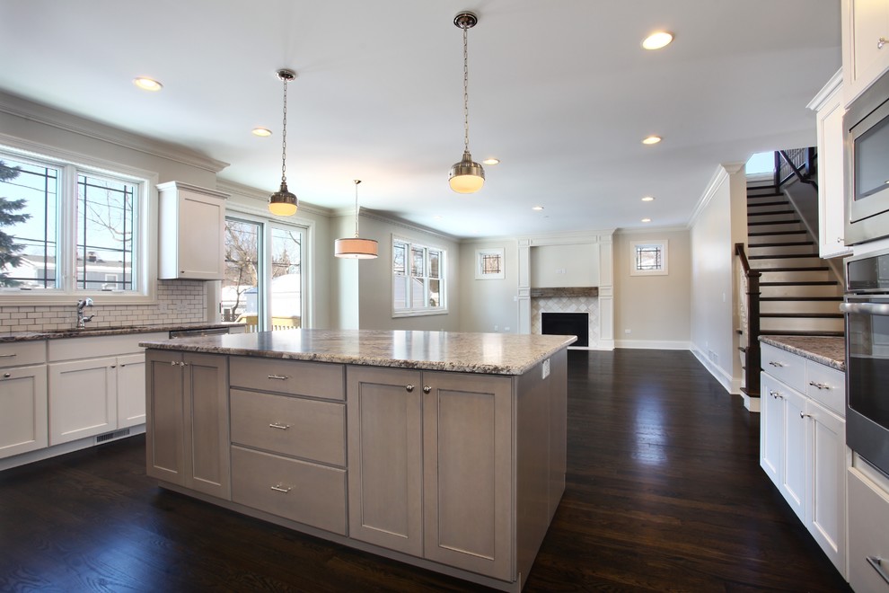 Inspiration for a large transitional u-shaped dark wood floor open concept kitchen remodel in Chicago with an undermount sink, recessed-panel cabinets, gray cabinets, granite countertops, white backsplash, ceramic backsplash, stainless steel appliances and an island