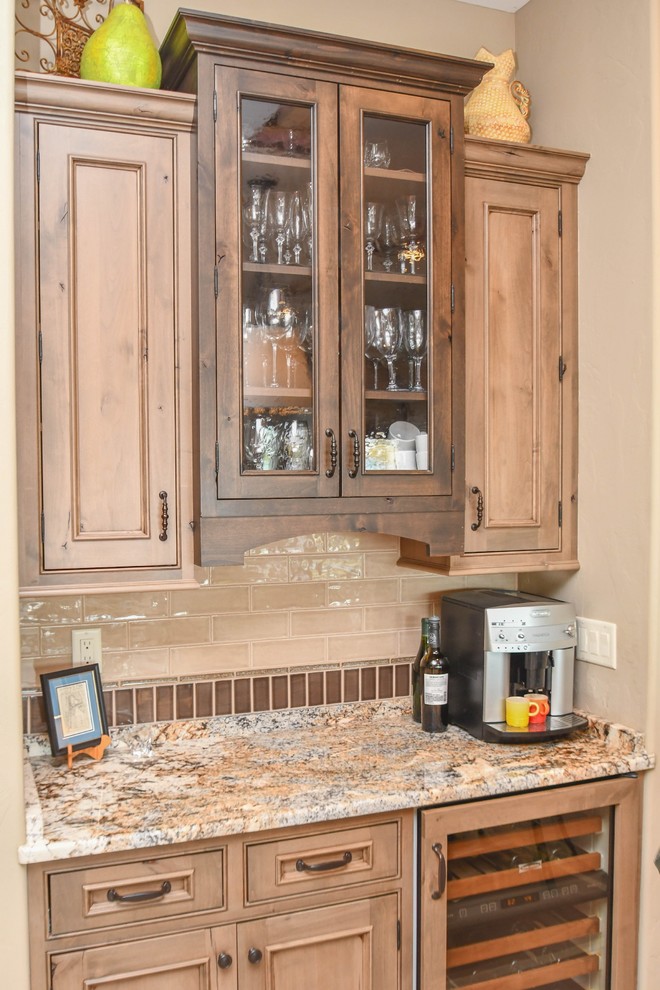 This is an example of a large transitional u-shaped kitchen pantry in Milwaukee with flat-panel cabinets, brown cabinets, granite benchtops, beige splashback, ceramic splashback, with island and multi-coloured benchtop.