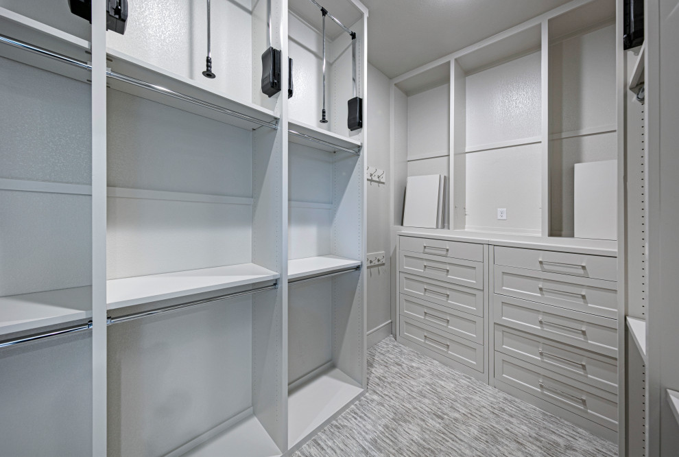 Large transitional gender-neutral walk-in wardrobe in Dallas with shaker cabinets, grey cabinets, carpet and grey floor.