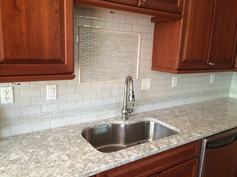 Inspiration for a transitional l-shaped dark wood floor kitchen remodel in Bridgeport with an undermount sink, raised-panel cabinets, granite countertops, gray backsplash and ceramic backsplash