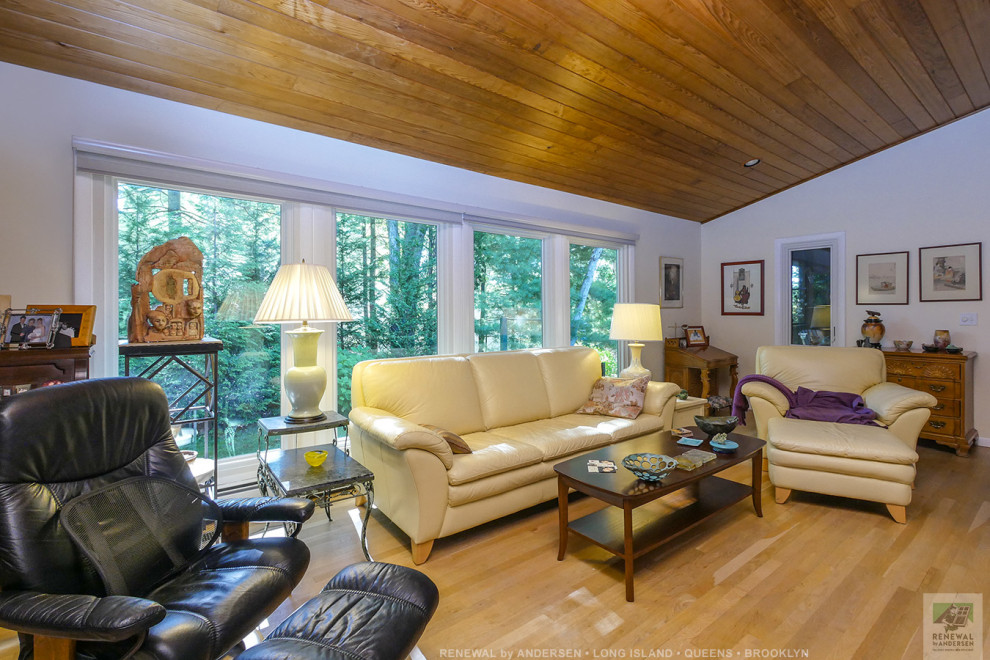 Mittelgroßes, Offenes Wohnzimmer mit lila Wandfarbe, hellem Holzboden, Kamin, freistehendem TV und Holzdecke in New York