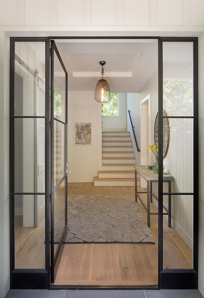 Inspiration for a large country front door in San Francisco with white walls, light hardwood floors, a single front door and a glass front door.