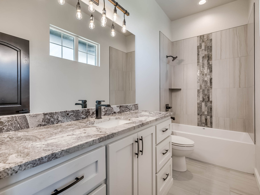 Photo of a large country bathroom in Oklahoma City with white cabinets, a shower/bathtub combo, black and white tile, glass tile, beige walls, porcelain floors, an undermount sink, quartzite benchtops, white floor, an open shower, a single vanity and a freestanding vanity.