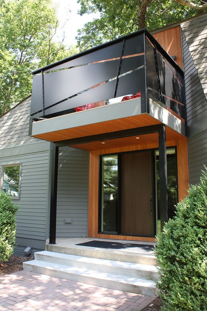 Expansive midcentury two-storey green house exterior in Cedar Rapids with concrete fiberboard siding and a shingle roof.