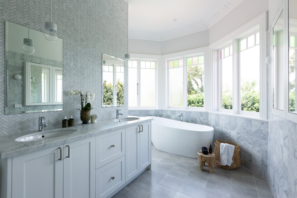 Design ideas for a transitional master bathroom in Sydney with shaker cabinets, white cabinets, a freestanding tub, gray tile, white tile, mosaic tile, beige walls, an undermount sink, grey floor and white benchtops.