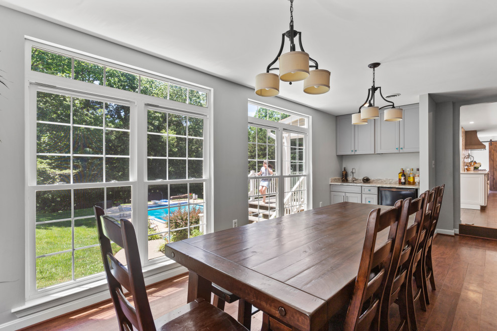 Inspiration for a mid-sized transitional single-wall dark wood floor and brown floor eat-in kitchen remodel in DC Metro with a farmhouse sink, recessed-panel cabinets, white cabinets, quartzite countertops, white backsplash, glass tile backsplash, stainless steel appliances, two islands and white countertops