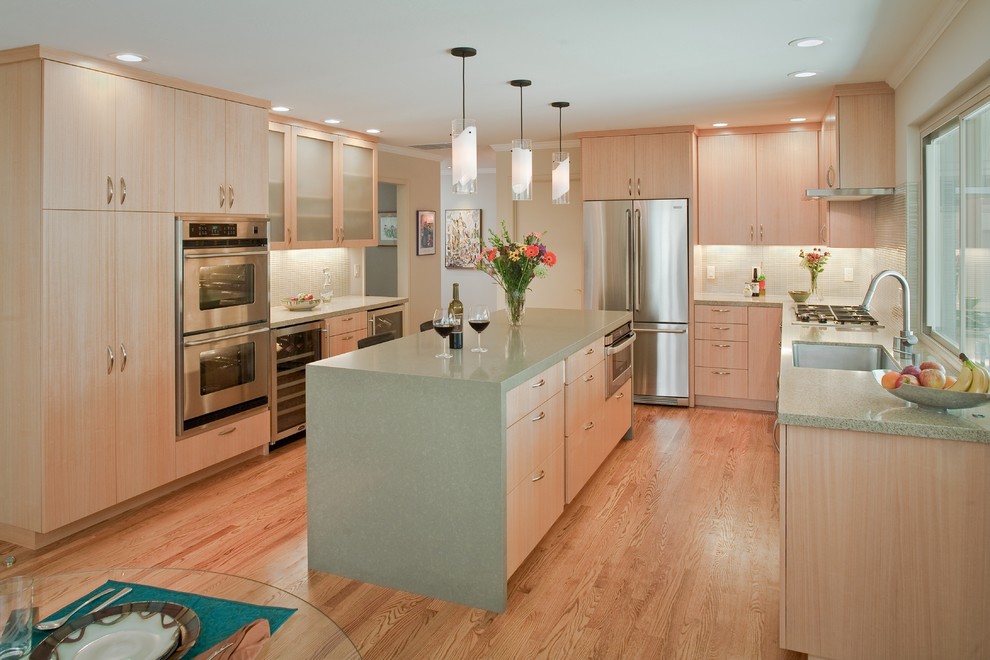This is an example of a mid-sized modern open plan kitchen in San Francisco with an undermount sink, medium hardwood floors, flat-panel cabinets, light wood cabinets, quartzite benchtops, beige splashback, stainless steel appliances and with island.