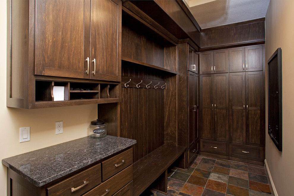 Inspiration for a mid-sized country gender-neutral walk-in wardrobe in Minneapolis with shaker cabinets, dark wood cabinets and terra-cotta floors.