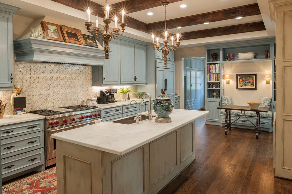Mid-sized traditional galley eat-in kitchen in Houston with a farmhouse sink, recessed-panel cabinets, blue cabinets, marble benchtops, multi-coloured splashback, cement tile splashback, stainless steel appliances, dark hardwood floors, with island and brown floor.