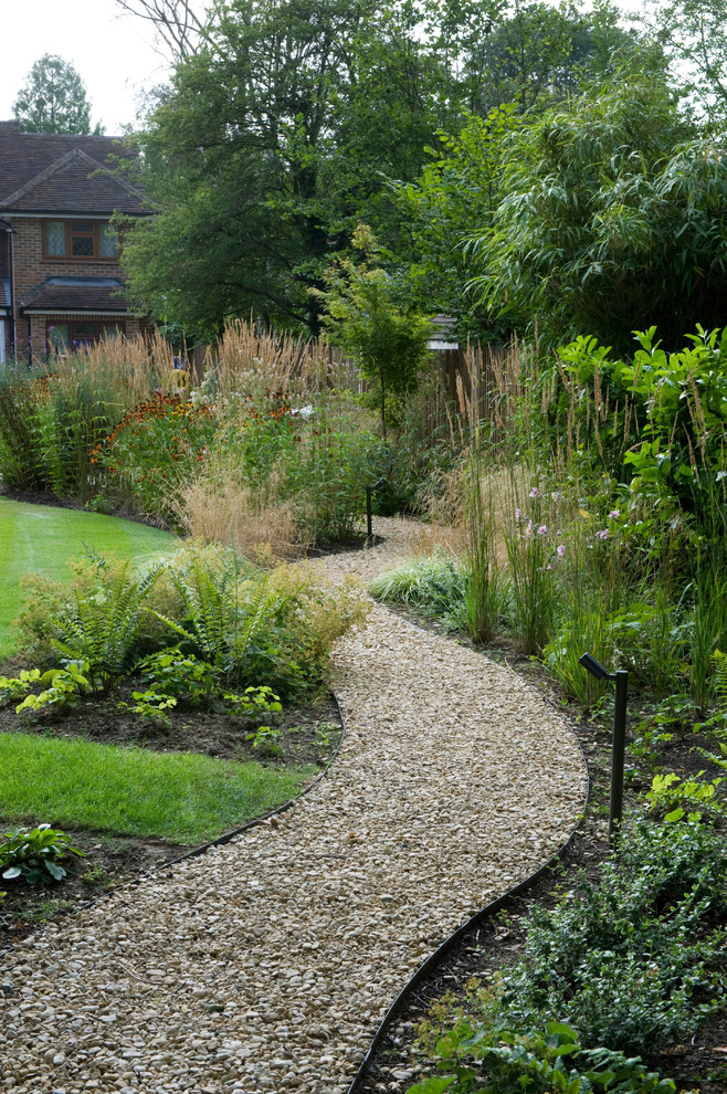 Large traditional backyard formal garden in Surrey with a garden path and natural stone pavers.