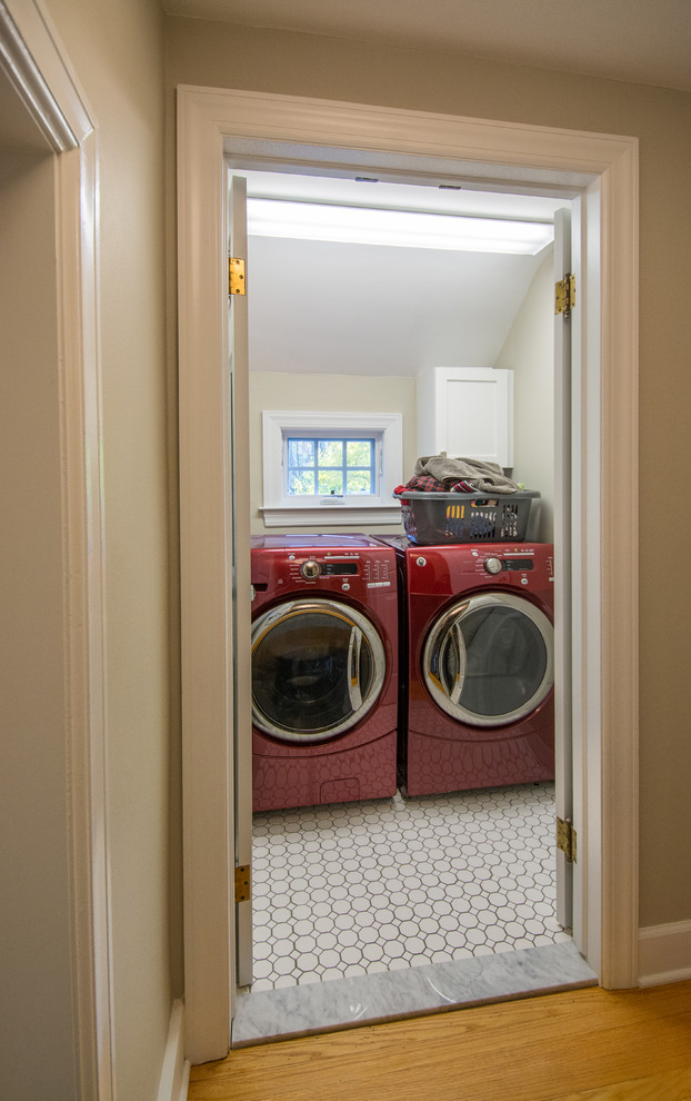 This is an example of a mid-sized traditional single-wall dedicated laundry room in Detroit with recessed-panel cabinets, white cabinets, beige walls, porcelain floors and a side-by-side washer and dryer.