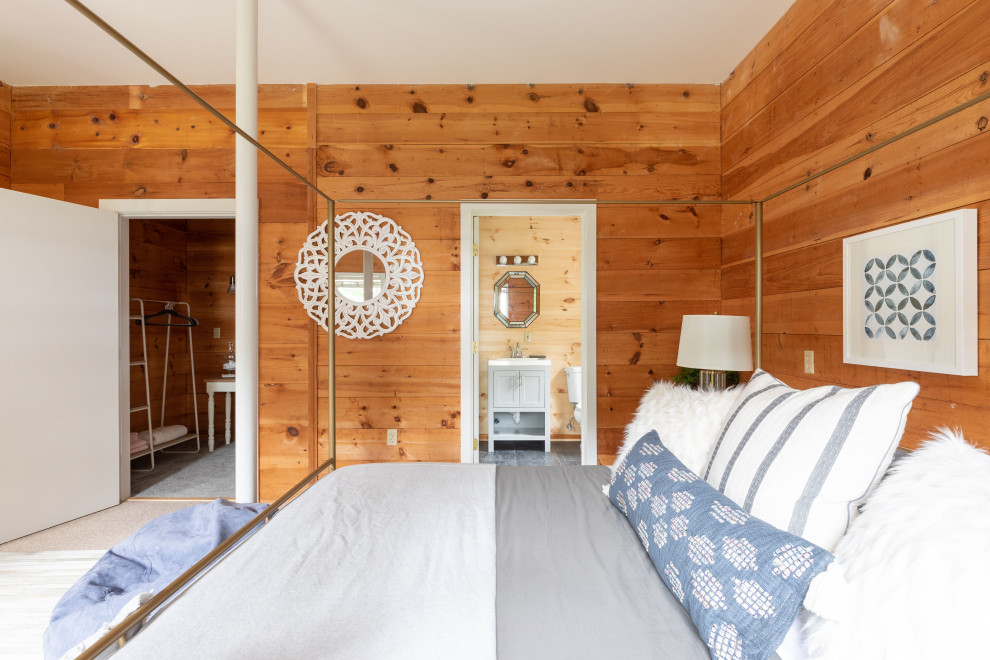 Large rustic master bedroom in Portland Maine with brown walls, carpet, beige floors and wood walls.