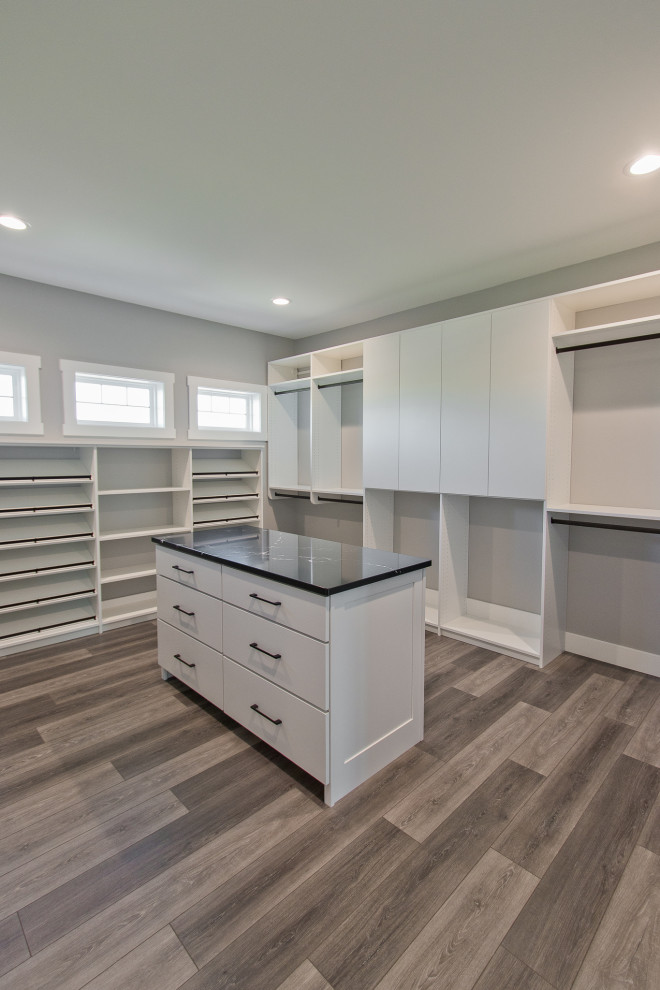 Walk-in closet - transitional gender-neutral vinyl floor and brown floor walk-in closet idea with flat-panel cabinets and white cabinets